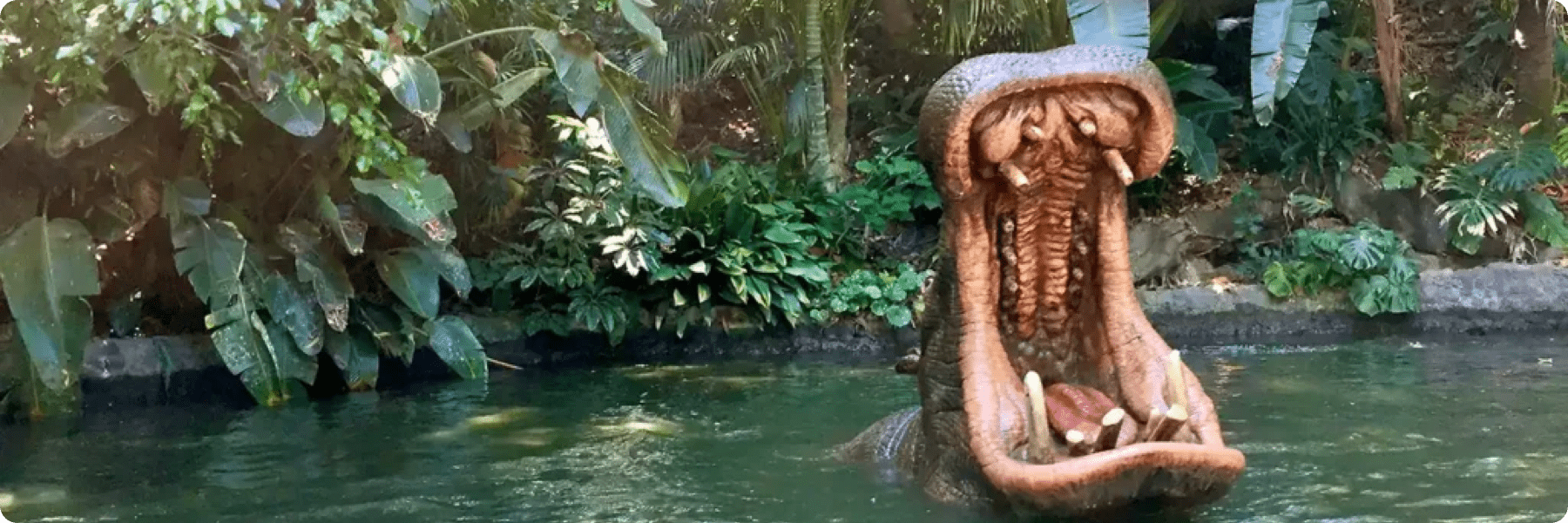 A large hippopotamus statue with its mouth wide open emerges from a water-filled environment surrounded by dense greenery, reminiscent of a jungle setting. This captivating scene could serve as an innovative backdrop for a creative marketing agencys next campaign.