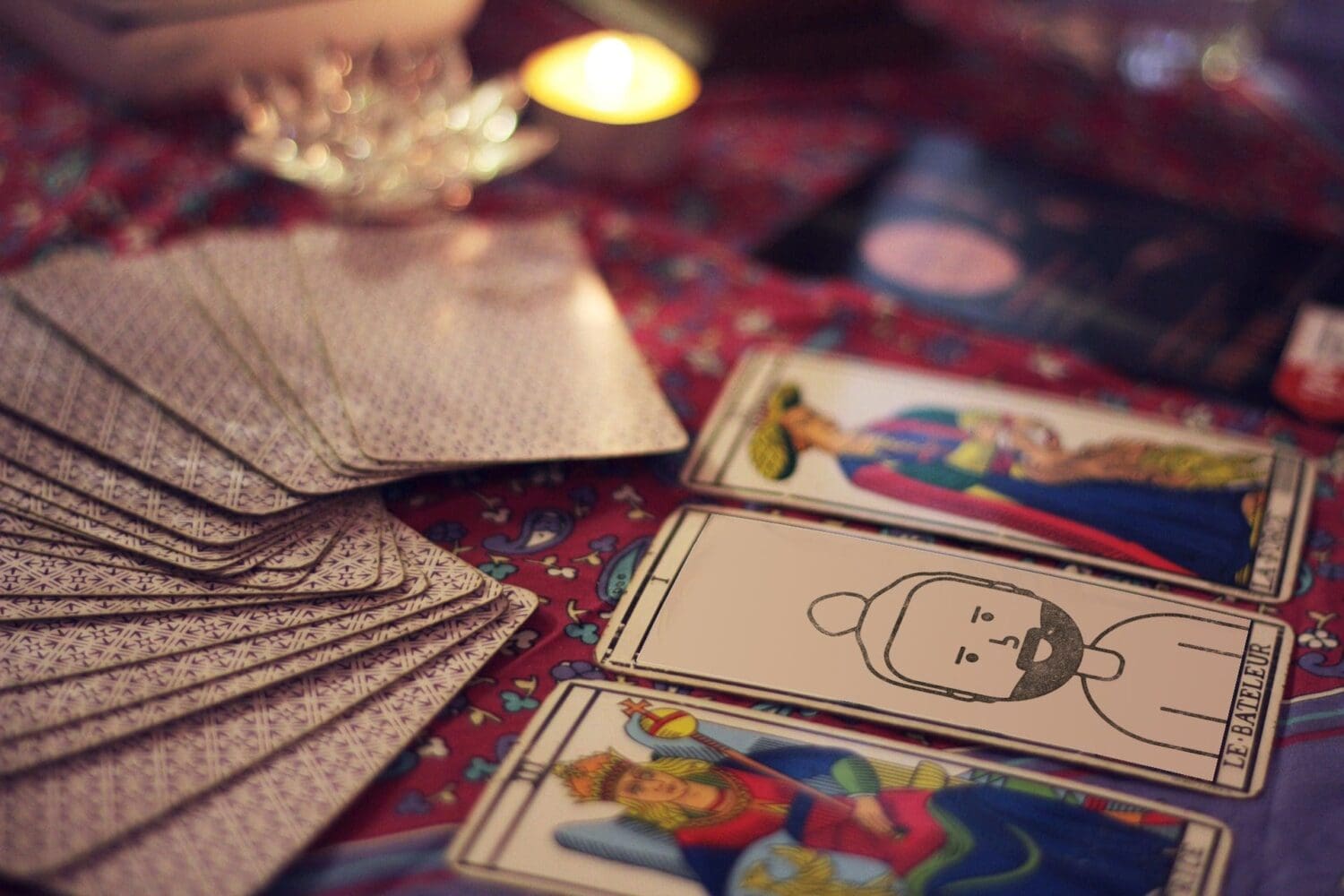 A table holds a spread of tarot cards, with a stack on the left. Three cards are face-up, featuring illustrated figures. A lit candle and decorative items are in the background, crafting a mystical atmosphere reminiscent of a marketing agencys creative web design process.
