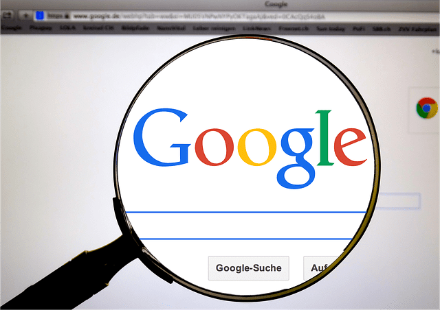 A magnifying glass enlarges the Google logo on a computer screen, emphasizing the search bar. The browser window displays tabs and bookmarks, capturing the essence of online browsing—a vital tool for any digital marketing agency aiming to harness search engine power for impactful digital marketing services.