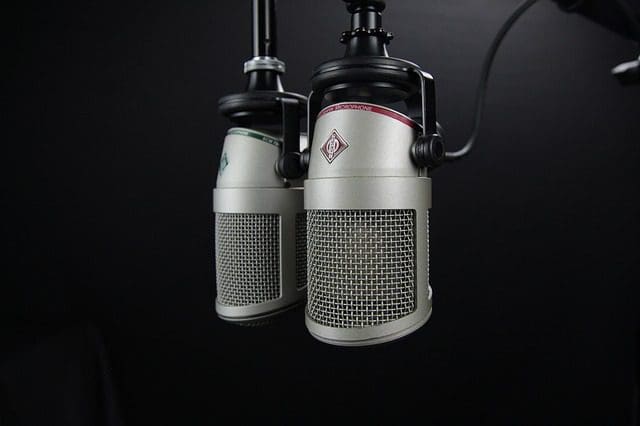 Two professional silver microphones with mesh grilles are suspended against a dark background, closely positioned as if ready for a polished audio recording or broadcasting setup—perfect for a marketing agencys podcast on SEO services and web design insights.