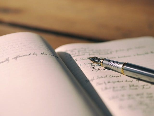A close-up image of an open notebook with handwritten text, featuring a fountain pen resting on one of the pages. The background is blurred, emphasizing the pen and writing, akin to how a digital marketing agency sharpens focus. The warmly lit scene creates a cozy atmosphere.