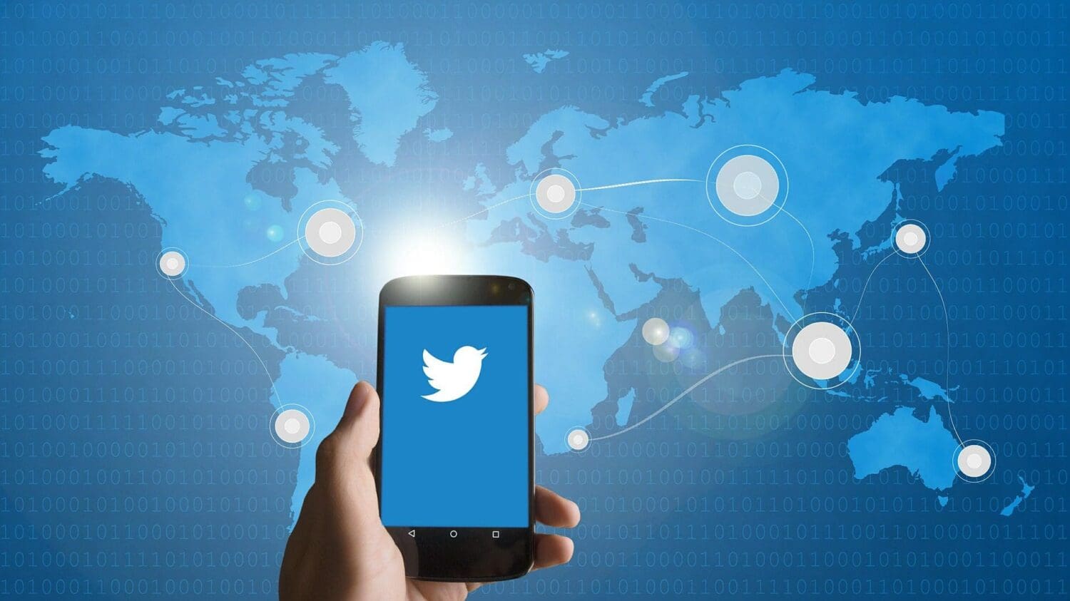 A hand holds a smartphone displaying a blue screen with a white bird logo. In the background, a world map highlights interconnected points, symbolizing global communication—a nod to SEO services bridging cultures in the digital landscape. The map is overlaid with binary code.