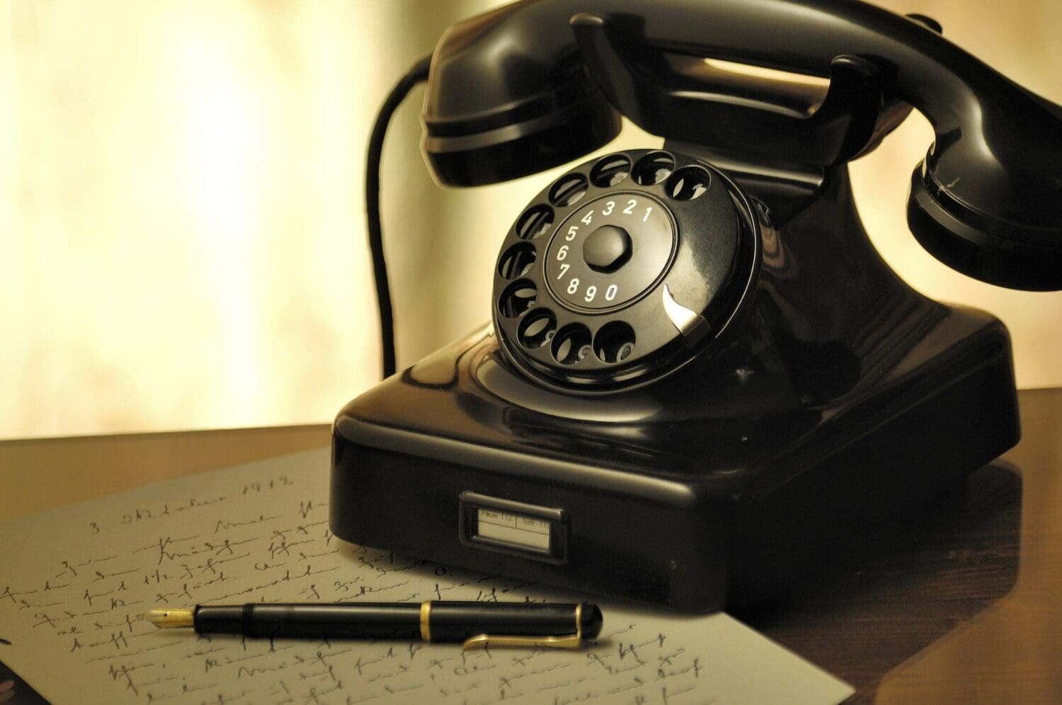 A vintage rotary phone sits on a wooden desk beside handwritten notes and a fountain pen, evoking nostalgia amidst modern times. The soft lighting creates a warm, historical feel, contrasting the digital marketing agencys bustling world with echoes of the past.