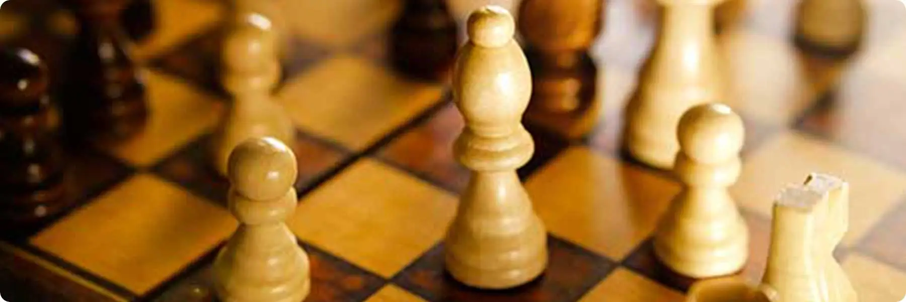 A close-up of a chessboard with several wooden pieces, including pawns and a bishop, captures the strategic depth akin to planning at a digital marketing agency. The checkered brown and beige board, with shadows cast by the pieces, mirrors the intricate tactics in digital marketing services.
