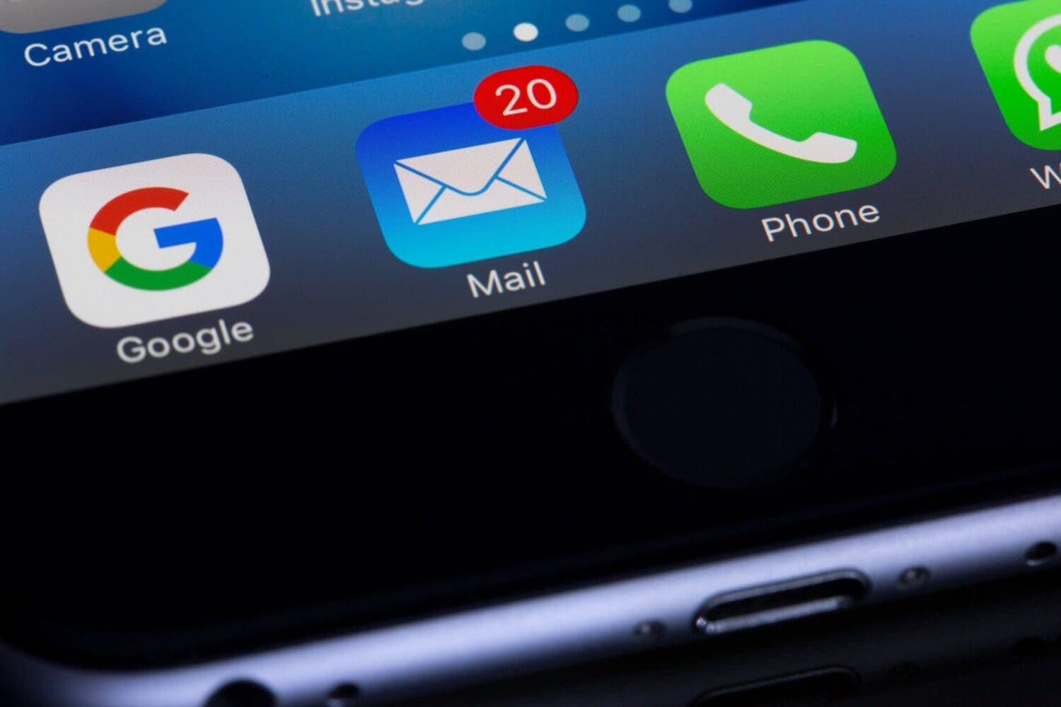 Close-up of a smartphone screen displaying app icons, including Google, Mail with a red notification badge showing 20 unread messages, Phone, and WhatsApp. Its like having your digital marketing agency right at your fingertips. The screens bottom edge and part of the phones frame are visible.