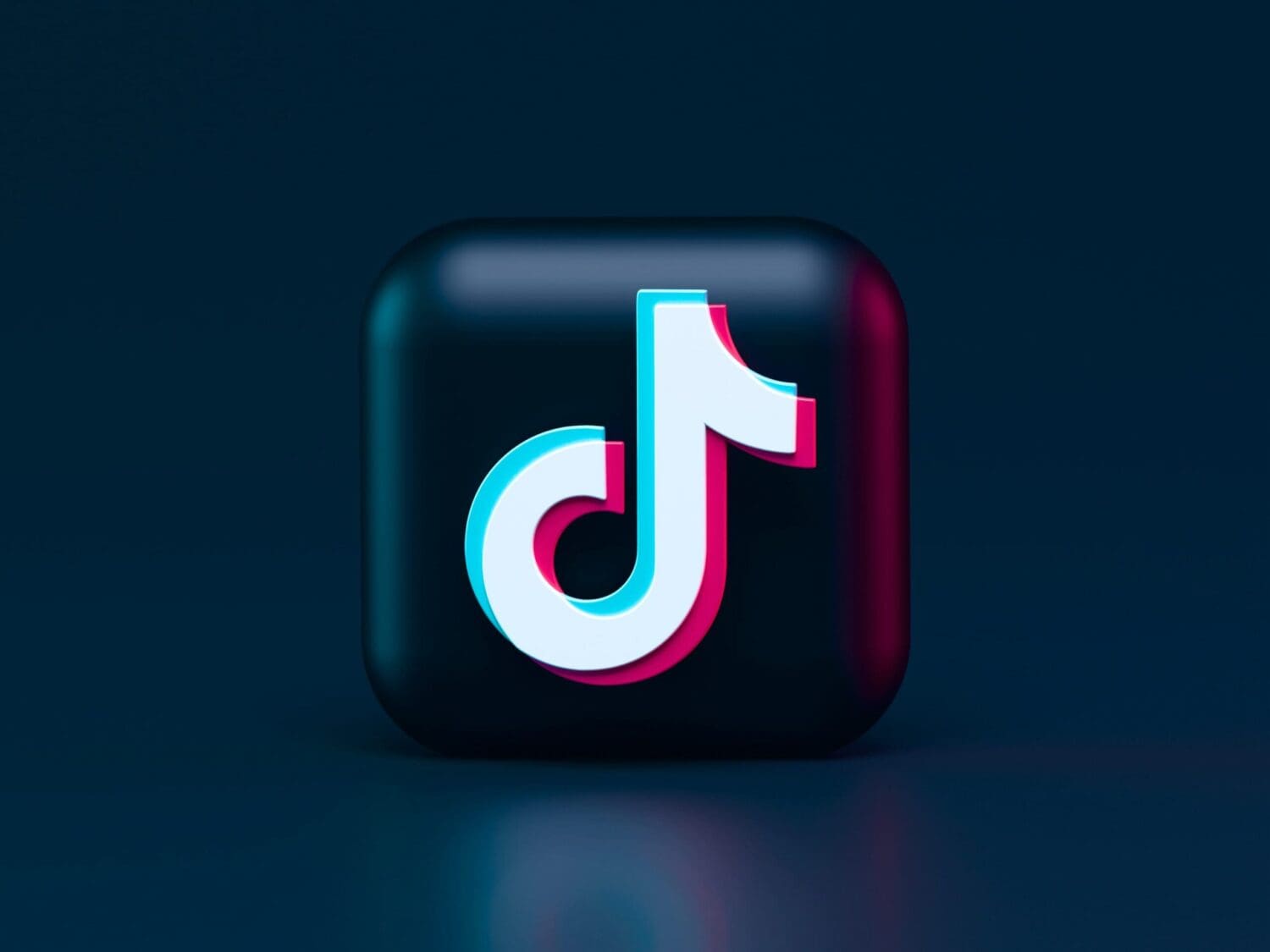 A 3D icon of the TikTok logo on a dark background represents a modern digital marketing company. The logo features a stylized eighth note in white with pink and blue accents, set against a glossy black square with rounded edges, embodying creativity and online engagement.