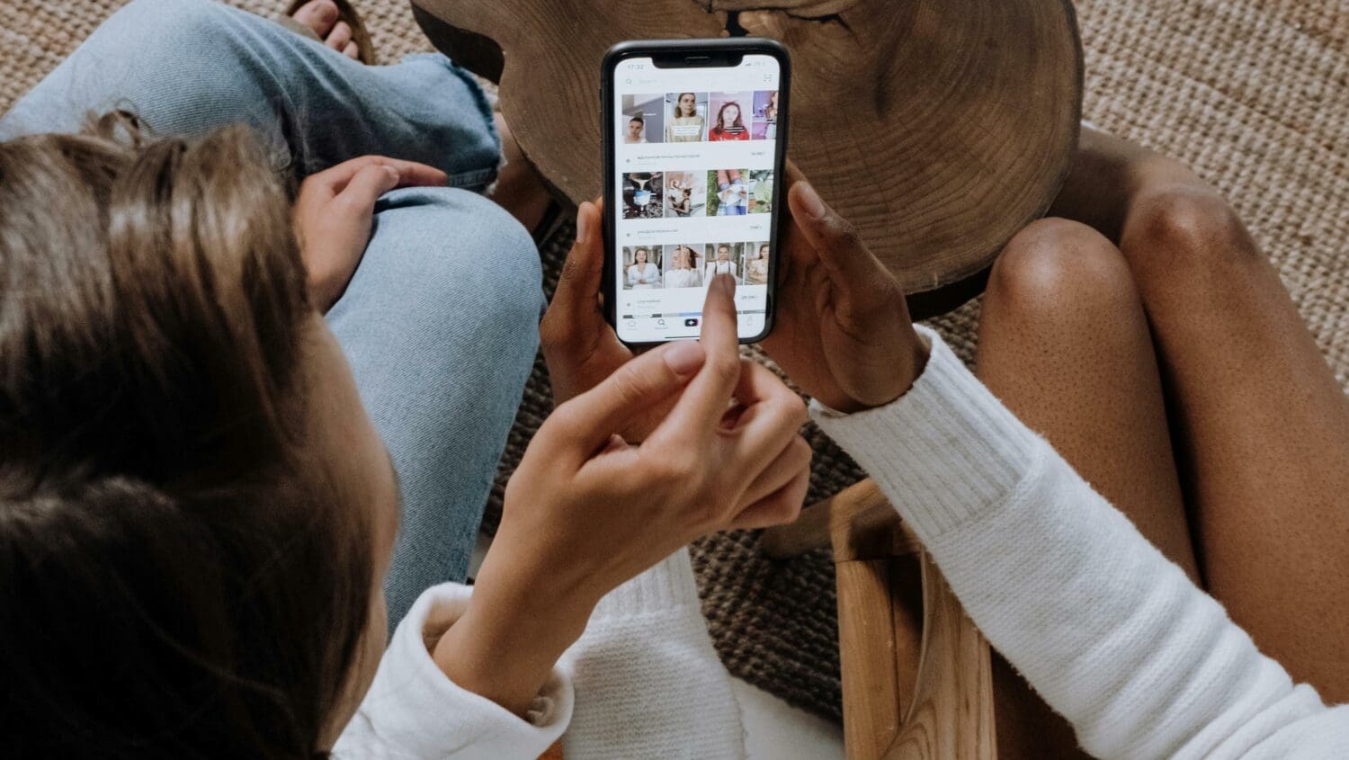 Two people looking at social media posts on a smartphone, with one person pointing at the screen.